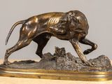 statue en bronze représentant un chien courant sur un rocher posé sur une table