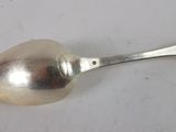 a silver spoon with a handle on a white surface