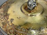 a silver and gold plate with a figurine on it