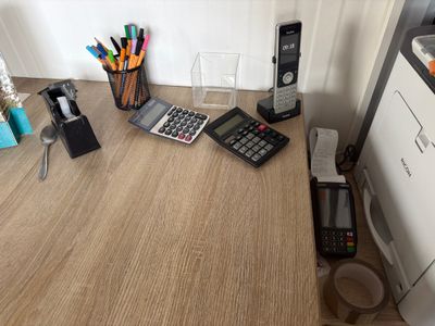 a desk with a calculator, a cell phone, a printer, and other office supplies on it