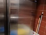 deux réfrigérateurs en acier inoxydable dans une cuisine, à côté d'une poubelle bleue