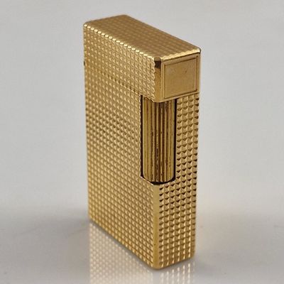 l'image d'un briquet doré posé sur une surface blanche