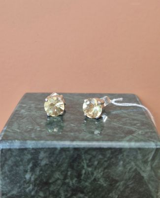 une paire de boucles d'oreilles à clous en diamant jaune posée sur un bloc de marbre