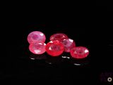 some red and pink glass beads are on a black surface