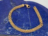 un gros plan d'un bracelet à chaîne en or sur une pierre bleue