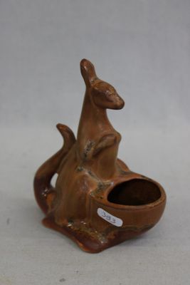 un petit kangourou en céramique tenant un bol dans la bouche