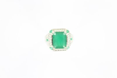 gros plan d'une bague avec une pierre verte entourée de diamants