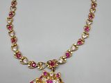 a gold necklace with pink and white stones on it