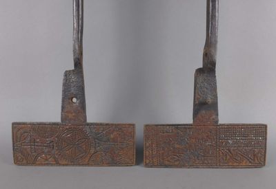 paire de marteaux anciens en fer, ornés de sculptures sur une surface grise