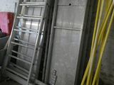 une échelle appuyée contre un mur, à côté d'un tas de matériaux de construction