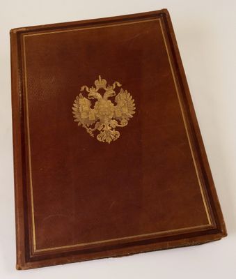 an old book with a gold emblem on it sitting on a white surface