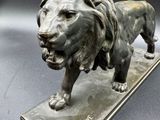 bronze statue of a lion on a base on a black background