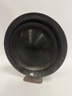 une photo représentant un bol en métal noir posé sur un socle en bois