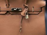a close up of a brown leather handbag with a lock on it