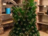 a large glass vase filled with green bottles in the middle of a room