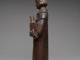 an old wooden statue of a man holding a book
