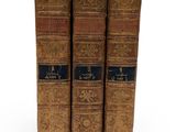 three old books sitting on top of each other on a white surface