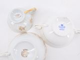 three white porcelain teapots and saucers on a white surface