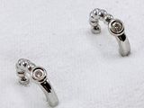 pair of diamond stud earrings on a white towel on a white surface