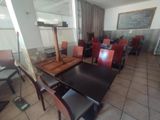 tables and chairs in a room with a large painting on the wall