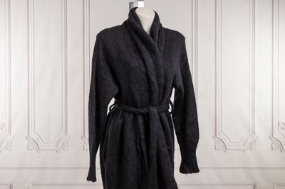 Le manteau est noir et est muni d'une ceinture.
