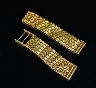 a pair of gold metal bracelets on a black surface