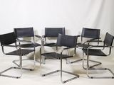 quatre fauteuils en cuir noir et une table dans une pièce blanche