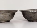 pair of silver metal bowls on a white surface with a white background