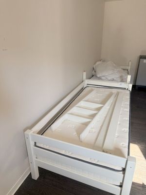 a white bed with a wooden frame in the corner of a room
