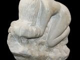 a white stone sculpture of a hand holding a rock