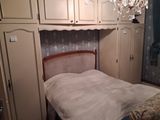 a bed in a small room with a chandelier hanging from the ceiling