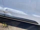 a car that has been dented and is parked on the side of the road