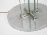 a glass table with a metal base and a lamp on it
