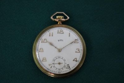 une montre de poche en or posée sur un tissu vert