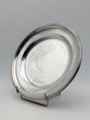 assiette en argent sur un support, sur fond gris avec un fond blanc