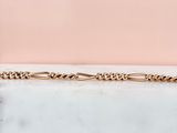 un gros plan d'un bracelet à chaîne en or posé sur une surface en marbre