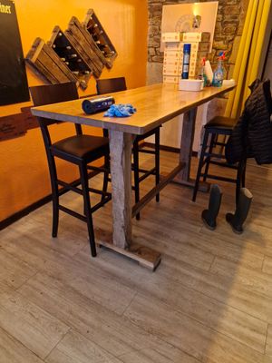 une table en bois avec des chaises et un tableau noir accroché au mur
