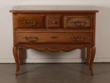 a wooden chest of drawers with marble top in a room