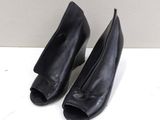 une paire de chaussures à talons hauts en cuir noir posée sur une surface blanche