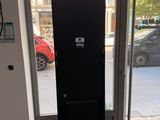 a tall black refrigerator sitting in front of a glass door