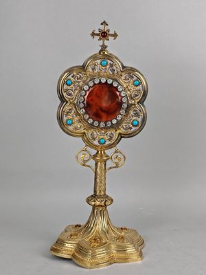 un miroir plaqué or orné d'une pierre rouge entourée de pierres bleues