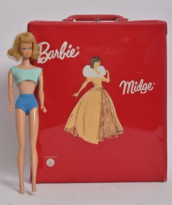 une poupée devant une valise rouge sur laquelle est posée une poupée Barbie