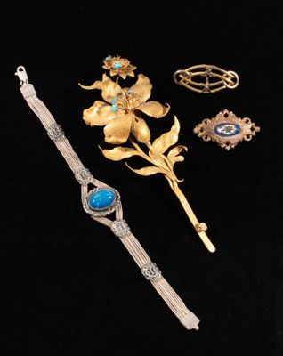 a close up of a bracelet, brooch, and other jewelry on a black surface