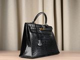a black crocodile skin handbag sitting on top of a wooden table