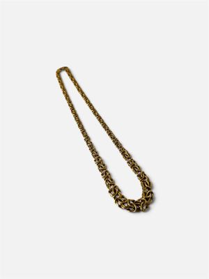 gros plan d'un collier en chaîne en or sur fond blanc