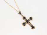 a gold cross pendant with blue sapphires on a gold chain