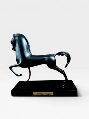 statue d'un cheval noir sur un socle noir, sur fond blanc