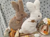 two stuffed bunnies sitting on a table with other stuffed bunnies