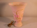 un vase rose avec une anse dorée posé sur une table blanche