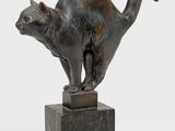 une statue en bronze représentant un chat debout sur un bloc de marbre